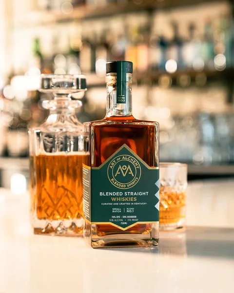 Blend No. 1 standing on the bar between a cut-glass decanter and a filled rocks glass, the back bar soft behind it.
